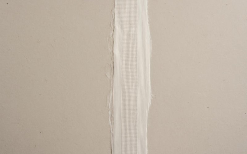 AI concept: Paper tape and compound on a drywall seam