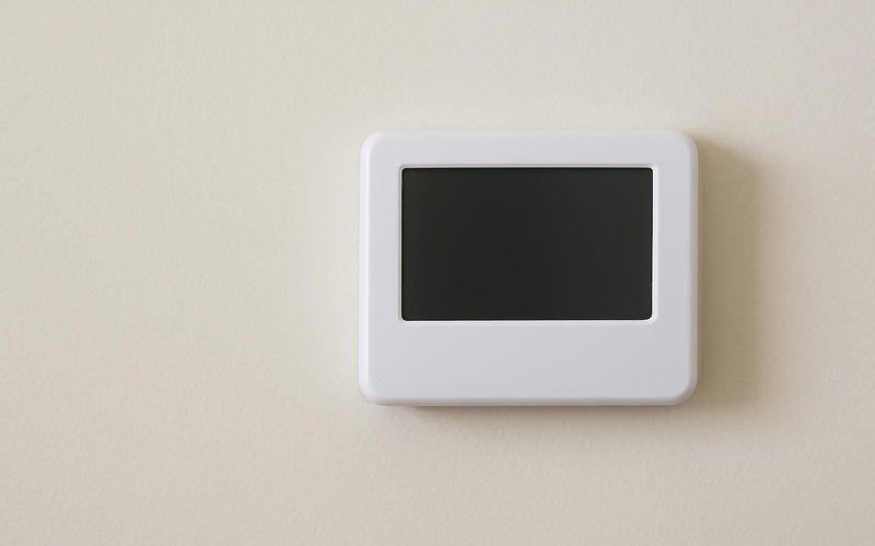 AI concept: An unbranded thermostat with a completely blank unlit screen on a clean interior wall