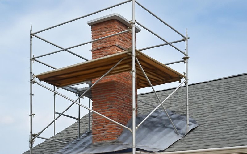 AI concept: Scaffolding around a brick chimney with roof protection