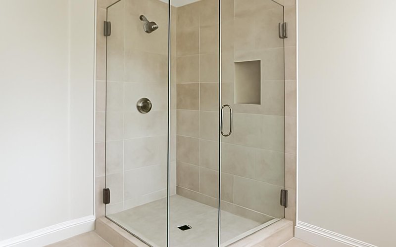 Frameless glass shower enclosure with brushed hardware