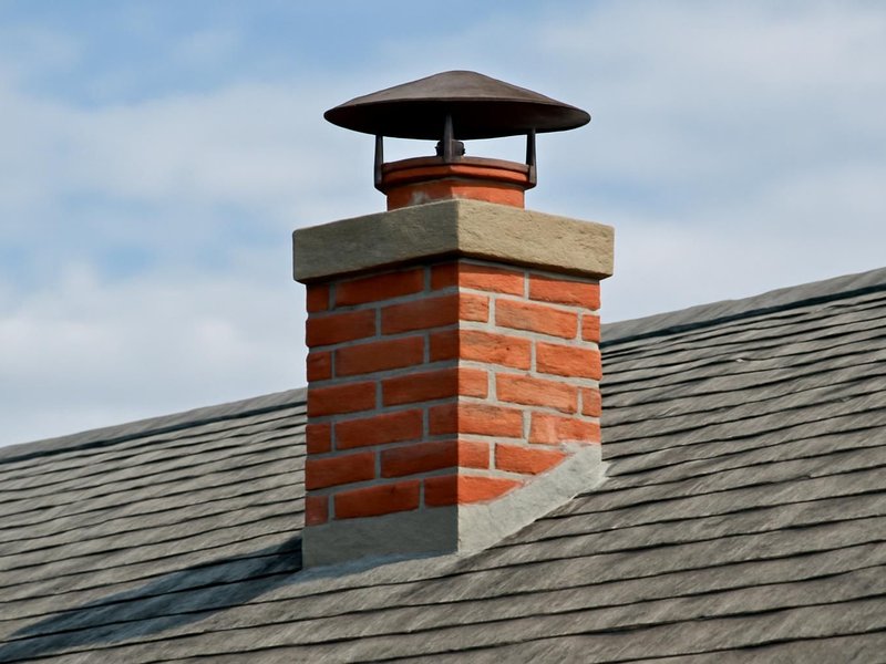 AI concept: A real-looking brick chimney on a shingle roof with visible open clay flue extending above the crown and a raised metal rain cap with clear ventilation gap