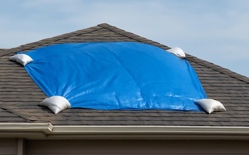 AI concept: Blue emergency tarp secured over part of a roof