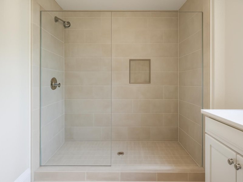 After: 48-inch tiled shower with a fixed glass panel and niche