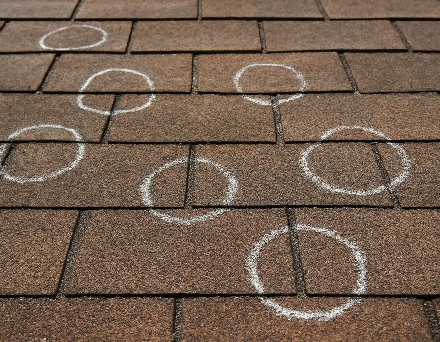 AI concept: Chalk circles marking hail hits on a test square of shingles